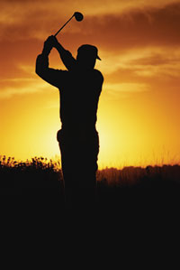 sun setting on golfer